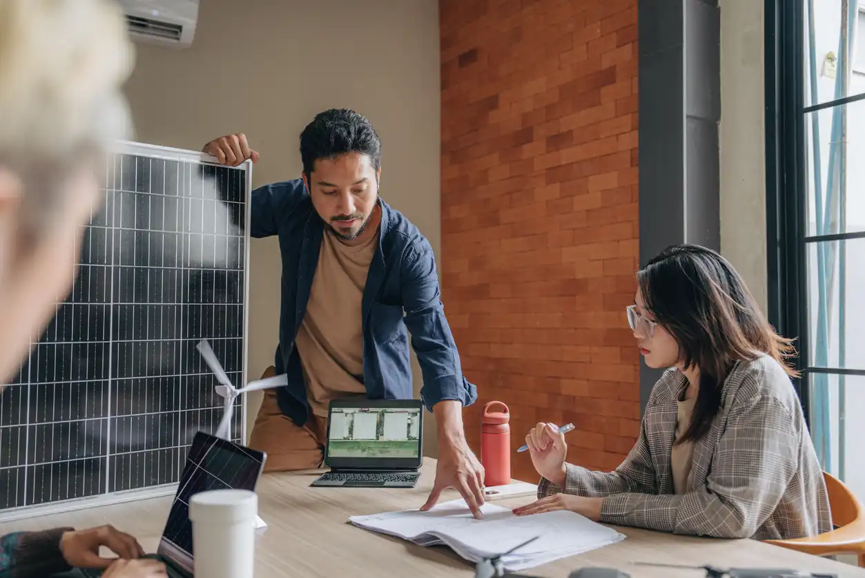 Equipe de profissionais analisando e discutindo dados em uma reunião sobre energia solar, sustentabilidade e geração de energia renovável.