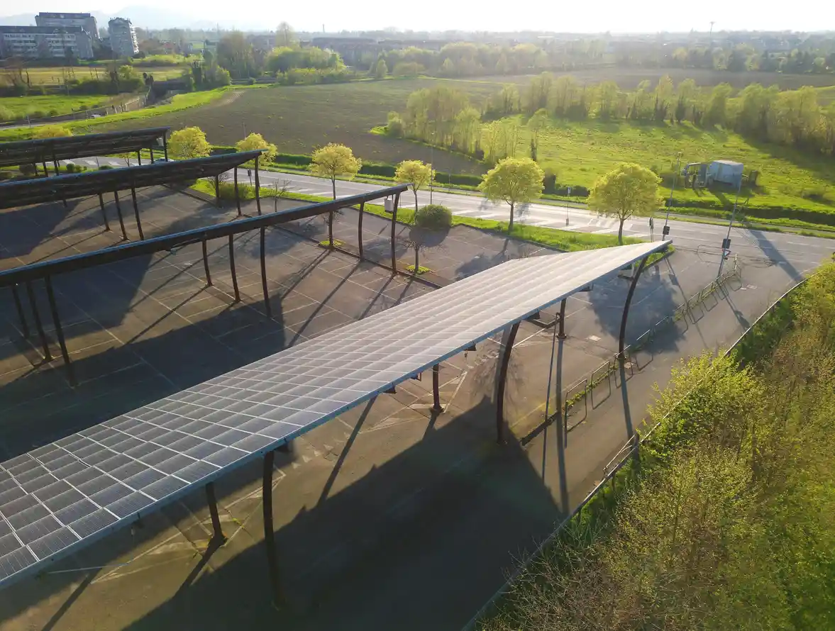 Conjunto de painéis solares instalados em estrutura metálica ao ar livre, aproveitando a luz solar em um ambiente de campo com árvores verdes e céu claro, promovendo energia renovável.